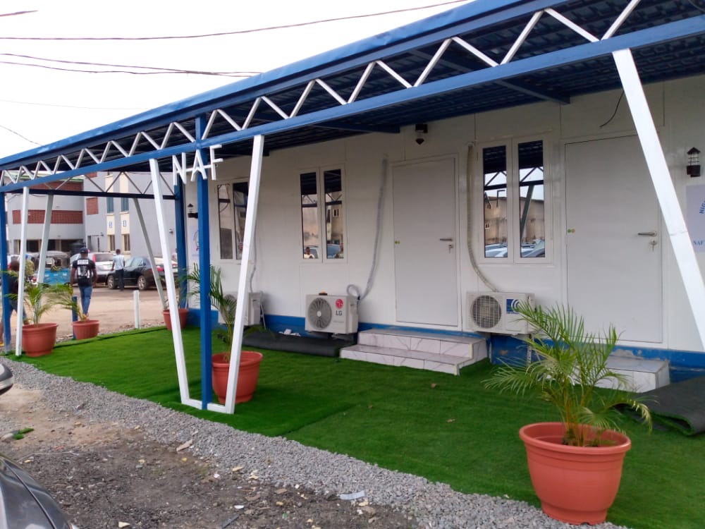 Row of container offices with a shaded walkway, air conditioners and planting